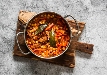 Slow cooker beef stew with chickpeas in a pot on a grey background, top view
