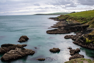 The rocky West Cork coastline with the sunseting and boulders covered in Irish sea moss. The seven heads cliffs are popular with hikers and hill walkers.