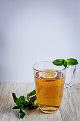 Kombucha tea in a glass. Super food pro biotic beverage in glasses with mint and lemon on wooden background - homemade healthy organic fermented probiotic drink