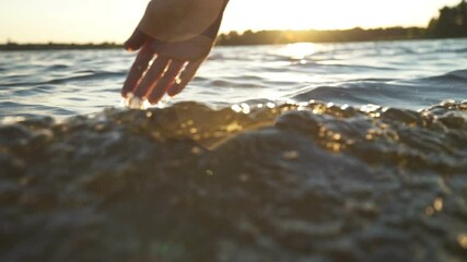 close up woman hand gently touches the surface of the water in the sea - Powered by Adobe