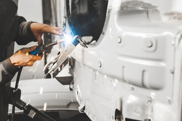 Worker repairing car body with carbon dioxide welding. Weld of auto.