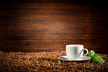 Coffee beans on a brown board with a green leaf
