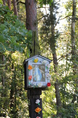 a small chapel in a tree with the Virgin Mary, decorated with colorful flowers