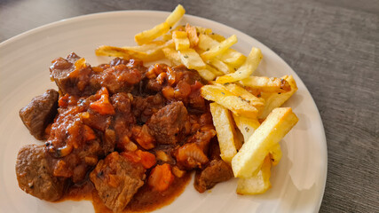 Lean beef in vegetable sauce accompanied with french fries