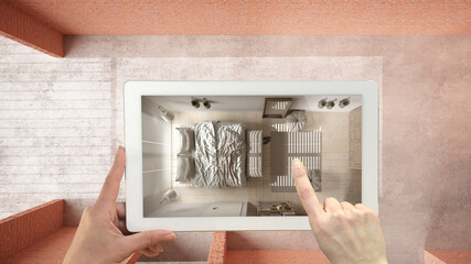 Augmented reality concept. Hand holding tablet with AR application used to simulate furniture, design products in interior construction site, bedroom with bed, top view, plan, above