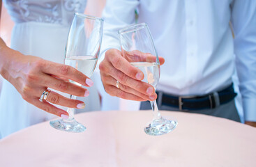 Beautiful wedding glasses in hands of the bride and groom