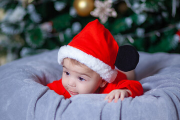 Cute baby wearing Santa suit near Christmas tree