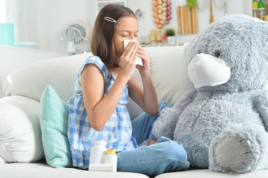 Girl coughing with toy bear in facial mask