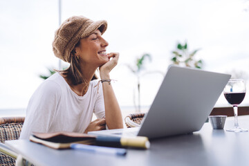 Happy caucasian female enjoying watching videos on free time on cafe terrace using wireless...