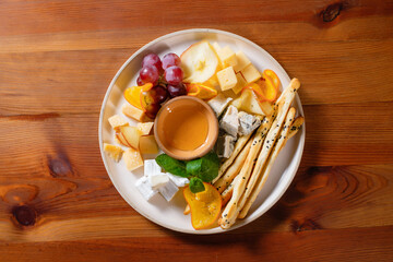 Fruit snack with grapes, cheese, croutons, honey, orange and pear.