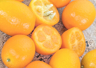 A hill of fresh kumquat fruits is a small citrus that is the size of walnuts. It is also called the fruit of the sages, fortunella, fairy tangerine, kinkan, golden bean or Japanese quince.