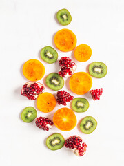 Seasonal healthy natural fruit composition - persimmon, kiwi, pomegranate slices