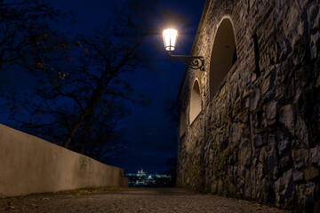 
light from street lighting and old stone fortress walls from the 15th century and paving blocks on...