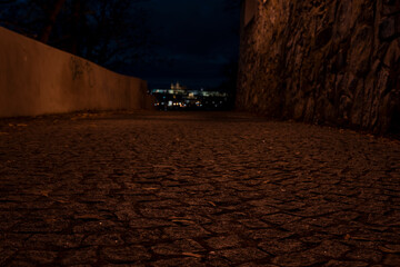 
light from street lighting and old stone fortress walls from the 15th century and paving blocks on the ground for pedestrians at night in the center of prague in the czech republic and in the backgro