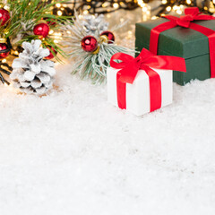 Gift boxes with a red ribbon under Christmas tree decorated with red balls and pine cones. Copy space.