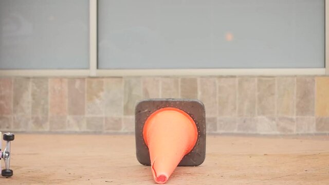 Camera focuses on the feet of the skateboarder. Skateboarder fails during his jump over the orange conus.