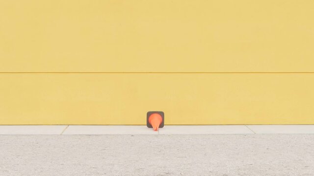 Skateboarder jumps over the road conus. Yellow background and teenager skateboarder jumps over the obstacle.