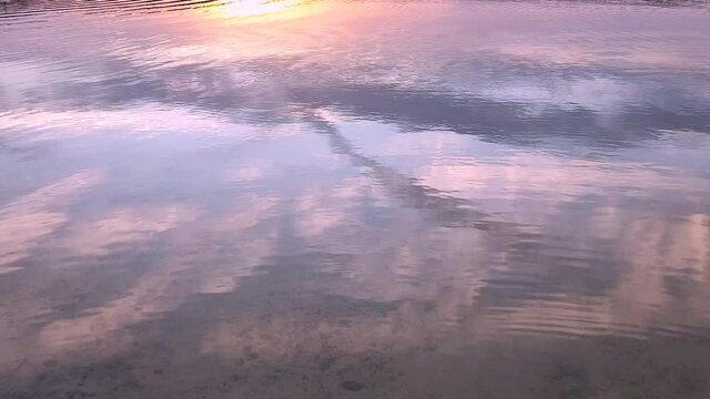 View of the reflection of the sky on the surface of the water in the lake at sunset.