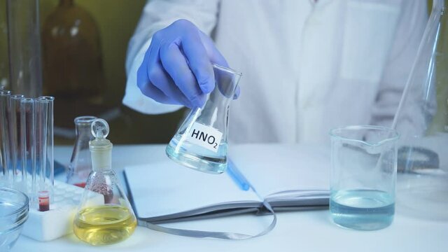 Chemical laboratory food supply. GMO Genetically modified products in the laboratory. A lab technician in a white coat holds nitric acid in his hand.