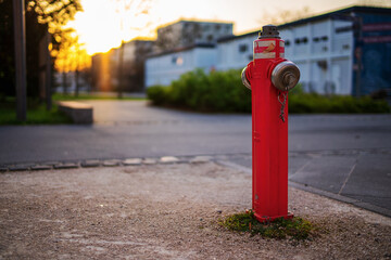 Fototapeta na wymiar Red water hydrant on the street in the evening with the sunset in the background