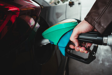 detail of a man's hand pouring gasoline into a car