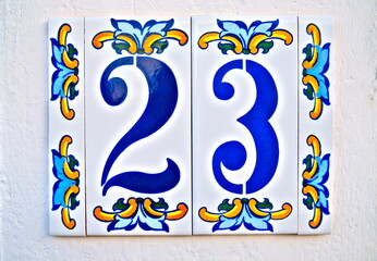 Number 23, twenty-three, blue digits on floral tiles, on a white background.