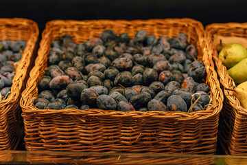 basket with fresh blue plums in grocery store. Image with selective focus