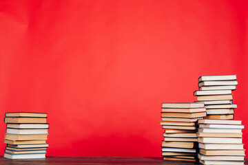 stacks of books for the education of knowledge in the school library on a red background place for inscription
