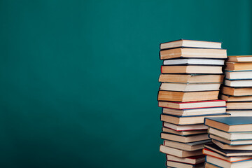 stacks of books for education in the university library on the green background of the place for the inscription