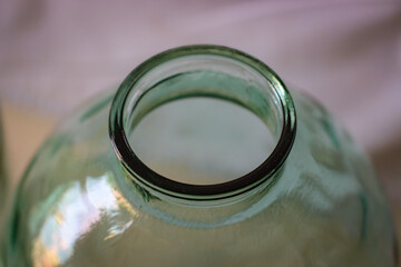 The neck of a huge glass jar on a light background