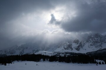 Dramatic winter view of Croda Rossa Di Sesto mountain from area around Alpe di Nemes refuge in Sexten Dolomites, South Tyrol, Italy. Stormy dramatic clouds and sun rays on sky.