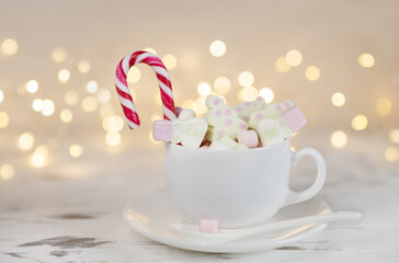 New Year background. A cup of cocoa with marshmallows on a white wooden background with bokeh. Close up
