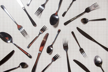 Many Cutlery forks, knives, spoons top view lie on a light background. The minimalist concept.