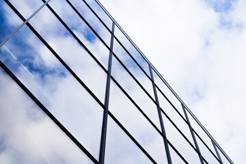 Modern glass facade of an office building, reflection of the sky in the Windows.