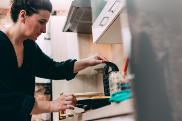 Woman baking waffles in kitchen, ready to take it out from waffle iron