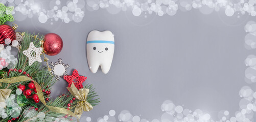 banner for dentistry for Christmas and New Year with tooth model on gray background with Christmas decor with copy space.