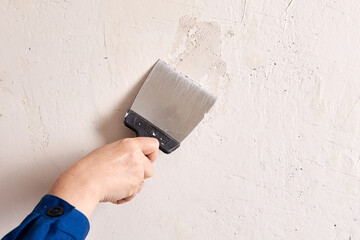 Applying skim plaster to wall with help of putty knife.