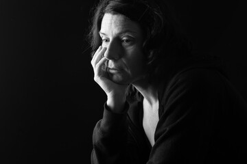 pensive woman with downcast eyes on black background