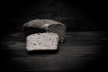 Homemade bread on a wooden background in black and white. Hunger abstraction
