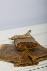 Homemade Nut & Dried Fruit Energy Bars. Wrapped in paper and tied with twine. On a white wooden box.