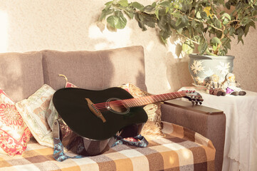 Black acoustic guitar in classic interior. Music lessons concept. Cozy living room with guitar on...
