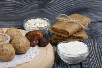 Dried fruit and oatmeal sweets. Nearby ingredients for their preparation. On black pine boards.