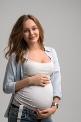 Cheerful pregnant woman in casual clothes in studio
