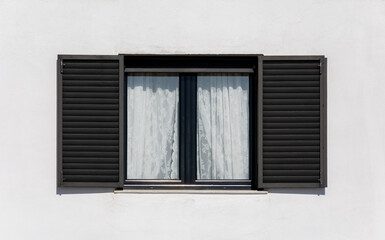 Wooden window with black shutters on a white facade