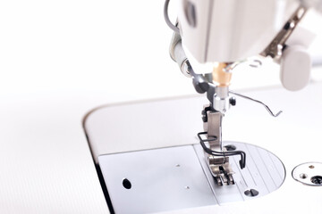 working area of a modern industrial sewing machine equipped with a narrow sewing foot for highspeed production of clothing - background blanked out blurry