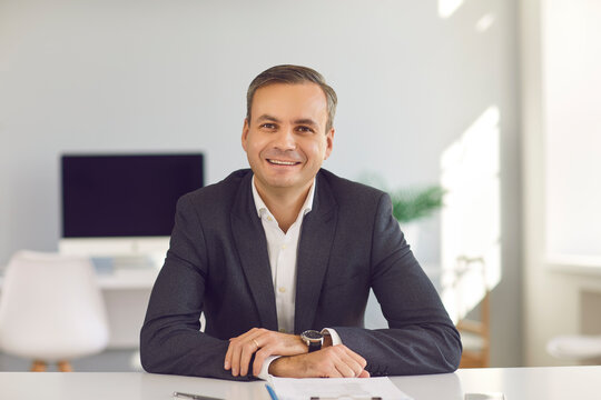 Young Smiling Businessman Sitting And Looking At Camera During Online Videocall In Office