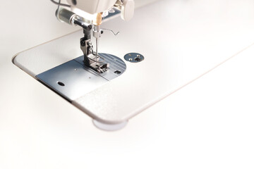 lower part of a modern industrial sewing machine equipped with a compensating sewing foot for highspeed seaming of borders - copy space for text - background blanked out blurry