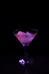 Glass with purple cocktail on black background