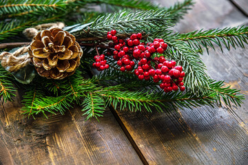 christmas festive background of spruce sprigs, pine cone and bunch of red berries on a wooden...