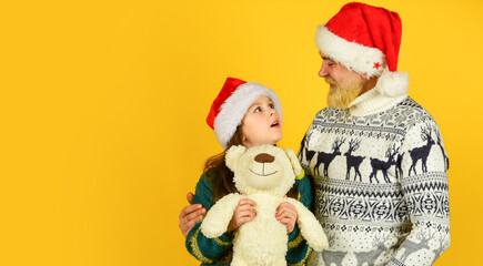 new year is here. bearded dad and small girl santa hat with toy. funny knitted sweater. copy space. father and daughter celebrate christmas. xmas party together. . winter family holiday
